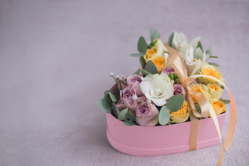 Stylish flowers arrangement in a pink hatbox. White orchid, purple and yellow roses with bunch. Birthday present. Flowers bouquet on background whith copy spase. Romantic concept