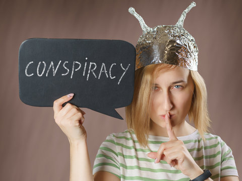Girl in a foil hat with a sign saying conspiracy
