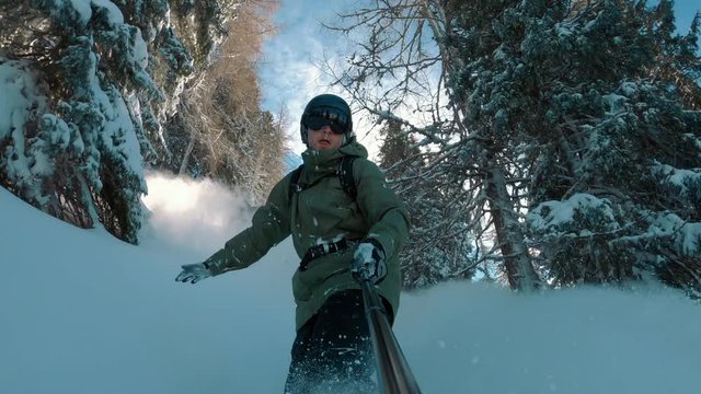 Happy snowboarder snowboarding down the slope on a perfect fresh powder snow day. A sunny winter day with blue sky.  Perfect travel destination, extreme sports. 