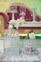 Wedding decoration. Two old ornamental cages decorated with colorful flowers. Two white decorative bird cages filled with flowers.