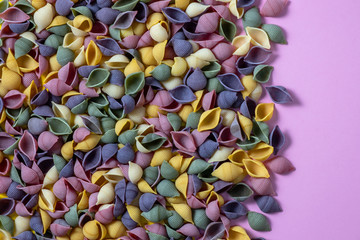 Pasta Conchiglie Rigate, mix of colorful uncooked shells with spinach and tomatoes. Textured Italian food background concept. Top view flat lay close up copy space