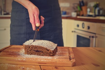 Man cutting classic gingerbreads in decorated kitchen. A classic gingerbread recipe. Family home bakery, cooking traditional festive sweets. Man cooking food.