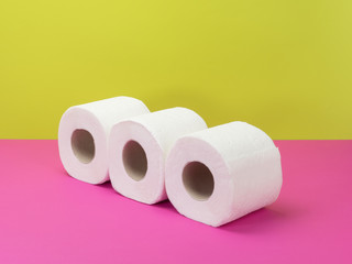 Toilet paper rolls on pink and green background.