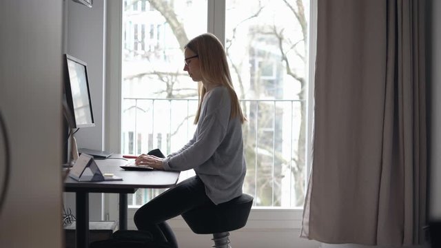 Frau arbeitet von zu Hause auf ergonomischen B&uuml;rostuhl