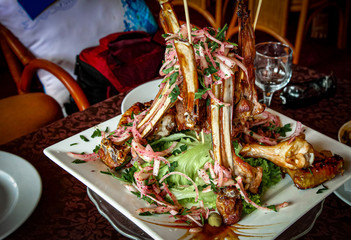 Lamb loin garnished with fresh lettuce with onion and barbecue chicken wings.