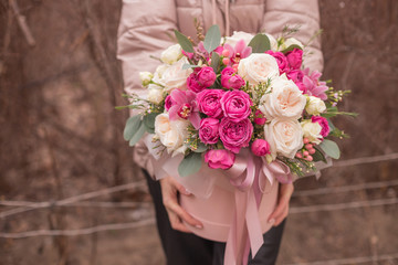 Woman florist making a lovely Flower composition in round hat box of  roses in girl hands.