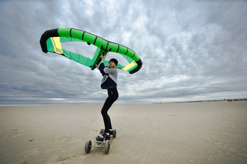 Une jeune femme sur une planche à roulette avec une aile pour se tracter