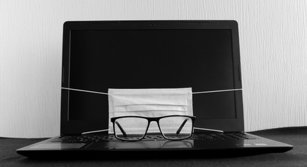 anti virus mask and glasses on laptop for safe working during quarantine