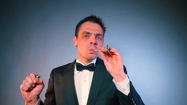 A man in a black suit smokes marijuana. Gray background. Legal Cannabis Use Concept