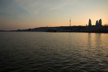 Naklejka premium Night view of Baku and the seaside of the Caspian sea. Sunset in Baku. Colorful sunset on the Baku boulevard . The seaside of the Caspian sea . Panorama Baku city in he morning, Azerbaijan .