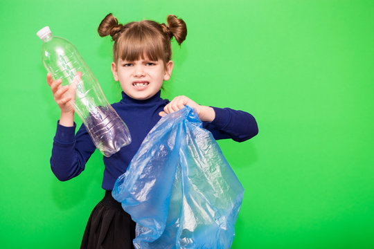 Little cute girl sorting plastic bottles into trash bag isolated on green background