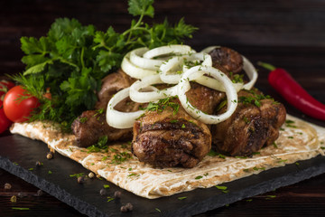 Fried chicken with vegetables and pita bread on a slate tray in a dark key