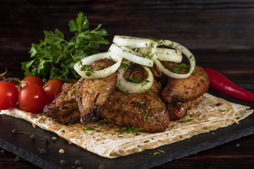 Fried chicken with vegetables and pita bread on a slate tray in a dark key