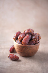 Dried date fruit in wooden bowl on wood textured background. Copy space. Superfood, vegan, vegetarian food concept. Macro of dates texture, selective focus. Healthy snack