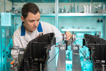 engineer measures plastic components for the production of lights for the automotive industry in a...