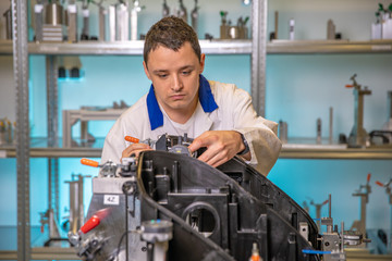 engineer measures plastic components for the production of lights for the automotive industry in a factory on a digital 3D machine