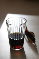 Glass of soda and sunglasses on a table. Selective focus.