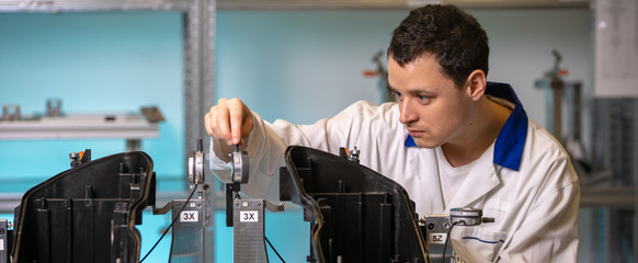 engineer measures plastic components for the production of lights for the automotive industry in a factory on a digital 3D machine