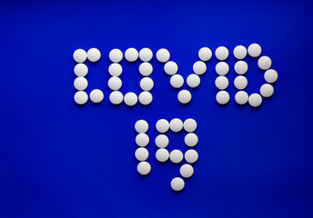 White pills on a colored background, medications, virus treatment, text covid-19