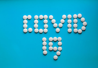 White pills on a colored background, medications, virus treatment, text covid-19
