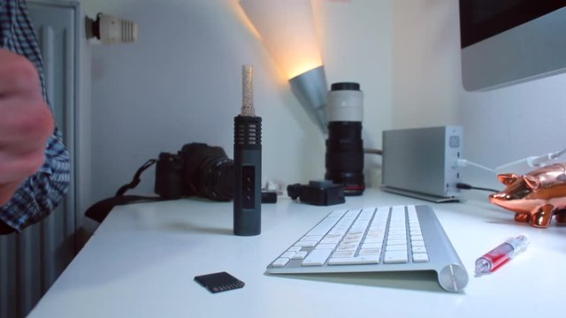 A businessman sitting at a table takes CBD cannabis from a bag and prepares to make a vaporizer. Legal use of marijuana.