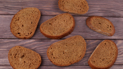 The dark rye bread cut into pieces and laid out on a wooden table.