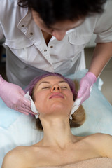Fototapeta na wymiar Beautician makes a procedure for a girl to improve facial skin condition