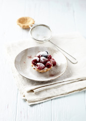  Little mascarpone tart with fresh raspberries on wooden background.