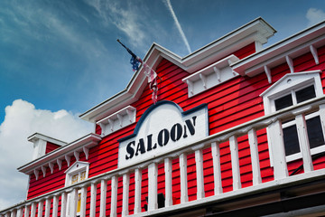 saloon wild west style with beautiful white balcony, red wooden wall and part of american flag