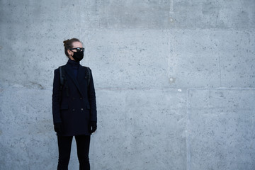 Young girl in a black protective mask and black sunglasses on the street, protecting against the virus