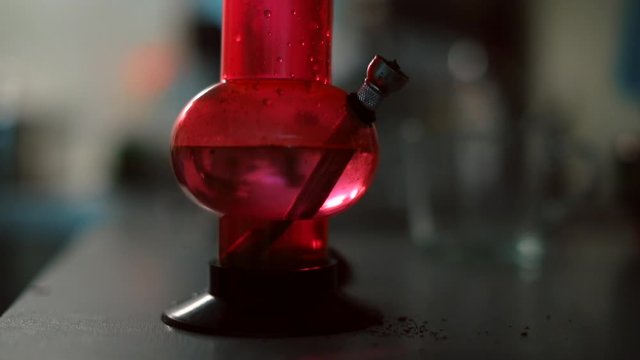 Close-up of a bong with a blinking light. A man smokes marijuana through a bong. Smoking appliance concept.