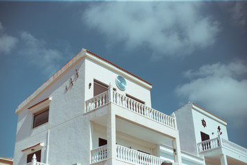 White two-story building with a clock against the sky