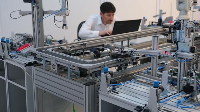 Industry 4.0 concept; Engineer is working on laptop to program smart factory prototype's automation. automated car on production line, artificial intelligence in smart manufacturing.