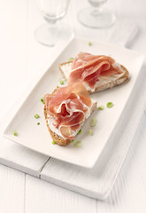 Sandwich with soft cheese and ham. Bright wooden background.