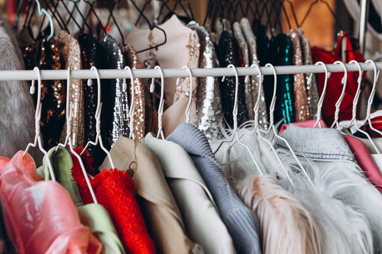 a lot of clothes hangers that are closely located next to each other in a store with women's clothing, an atmosphere of women's space with a large selection of colorful clothes