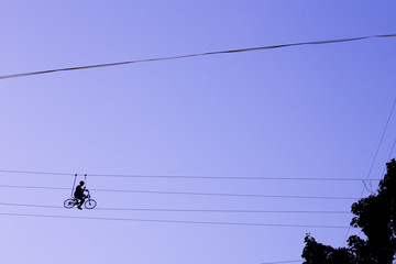 Man balancing on a bicycle on a rope © Hennadii