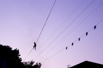 Man balancing on a rope against the sky