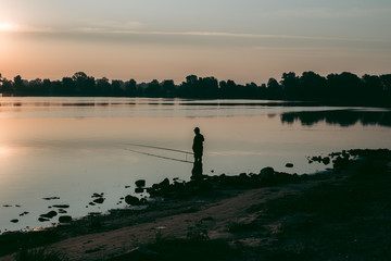 Obraz premium Fisherman at dawn fishing on a fishing rod