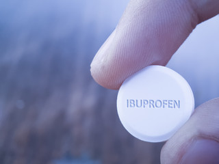 Holding tablet of Ibuprofen in hand with blurred background. Concept image for anti infammazory...