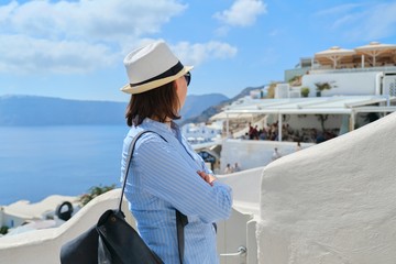 Fototapeta na wymiar Tourist business, businesswoman posing of landscape of Oia Santorini