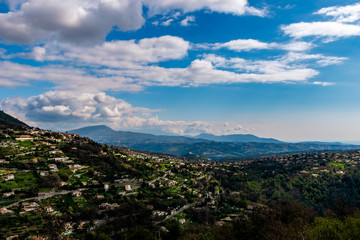 Fototapeta na wymiar A wide / high angle panoramic view of Saint-Jeannet buildings and other towns covering the low Alps mountains hills with the mountain ranges in the haze (French Côte d'Azur/ Provence/ Riviera)