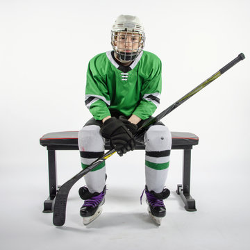 Male youth hockey player sitting on bench waiting to play