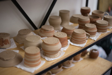 Pottery cups, plates made of clay dry on a shelf
