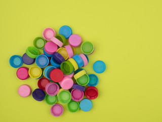 Colorful plastic caps for bottles on a bright green background.