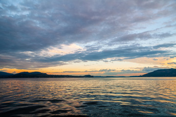 Panorama del Lago Maggiore al tramonto, con le montagne circostanti e cielo nuvoloso, Piemonte, italia
