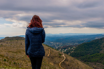 A back view shot of an unrecognizable  young redheaded woman standing enjoying the view of the vast...