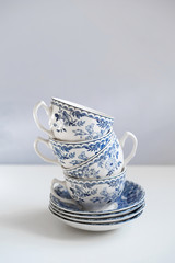 Porcelain saucers with a cup for tea in blue with flowers. New luxury elegance dinnerware on isolated white background. Trendy plate. Flat lay view.