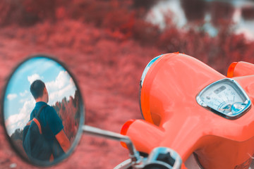 Reflection of a man in the side mirror of a motorbike
