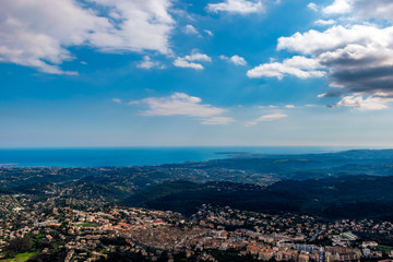 Fototapeta na wymiar A wide / high angle panoramic view of Vence buildings and other towns covering the low Alps mountains hills with the Mediterranean Sea coastline on the horizon (French Côte d'Azur/ Provence/ Riviera)
