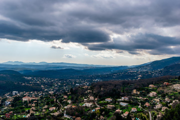 A wide / high angle panoramic view of houses and other buildings of several towns covering the low Alps mountains hills with the mountain ranges in the haze (French Côte d'Azur/ Provence/ Riviera)